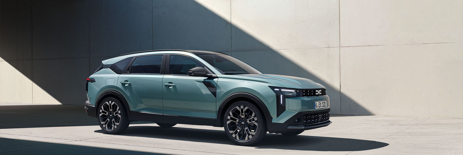 Ein türkisener Dacia Striker, ein neues Modell von Dacia parkt unter einer Brücke in einer modernen Stadt.