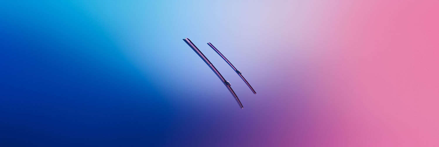 Sichtbar sind zwei Scheibenwischer vor einem Hintergrund der von Blau in Rosa verläuft.